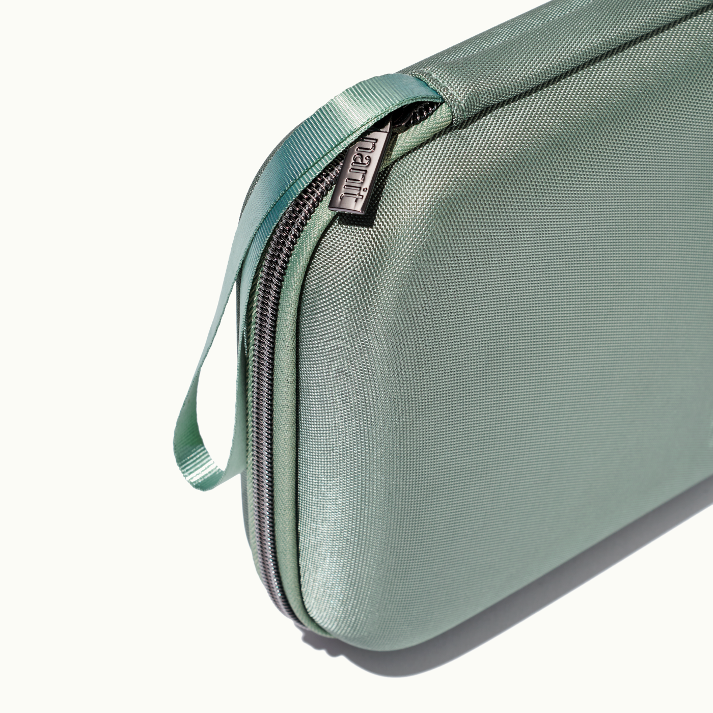 zoomed in picture of gray zipper and strap on green travel case