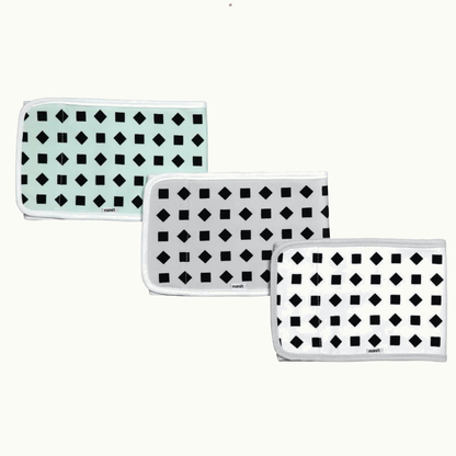 Three folded rectangular cloths with black geometric patterns—squares and diamonds—on white or light mint backgrounds, each bordered with white trim, arranged in a staggered row. #multicolor